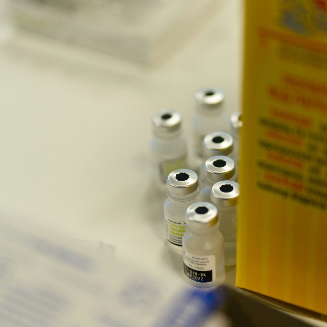 Vials next to packaging Group of small vials of medicine beside a yellow box.
